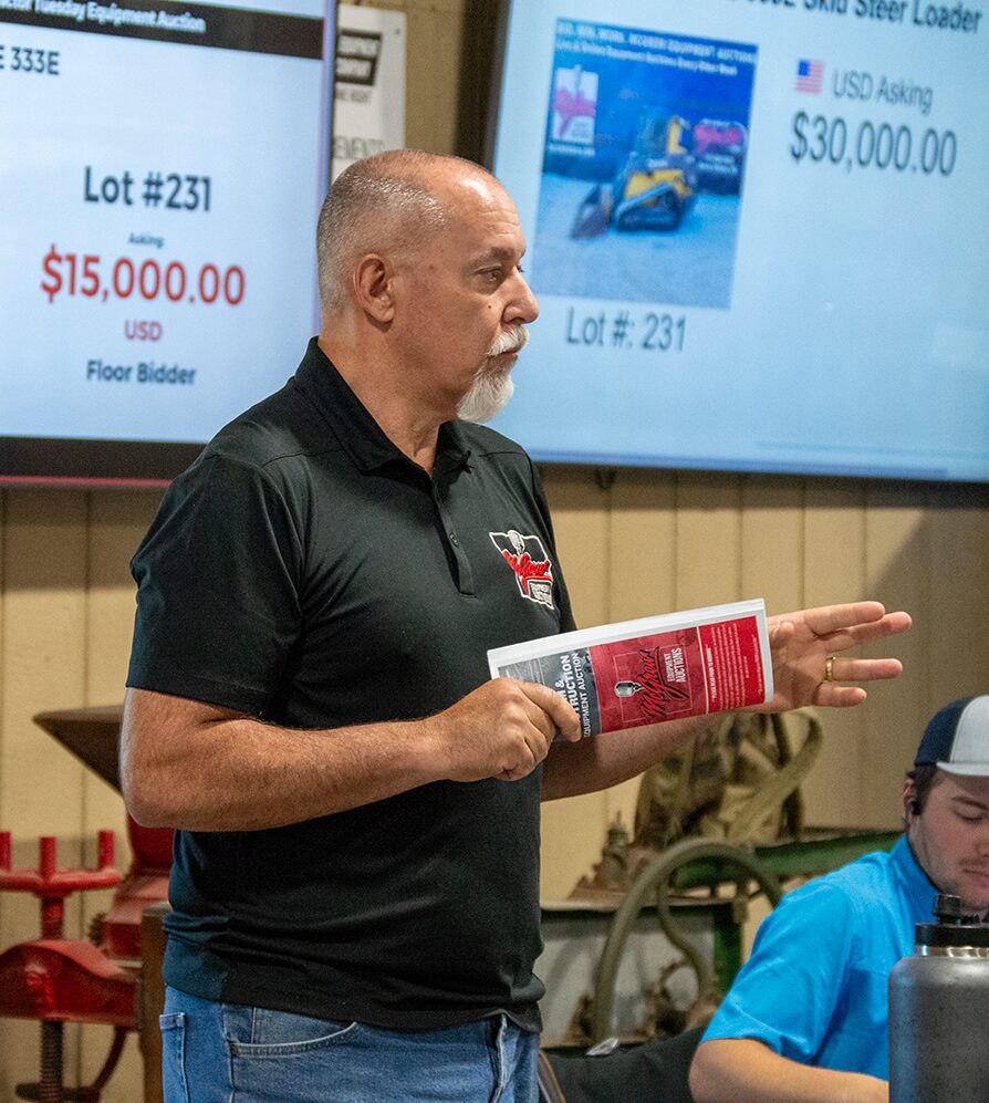 Auctioneer holding catalog at machinery auction
