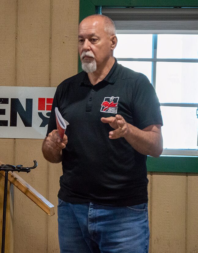 Man in black polo shirt presenting with papers