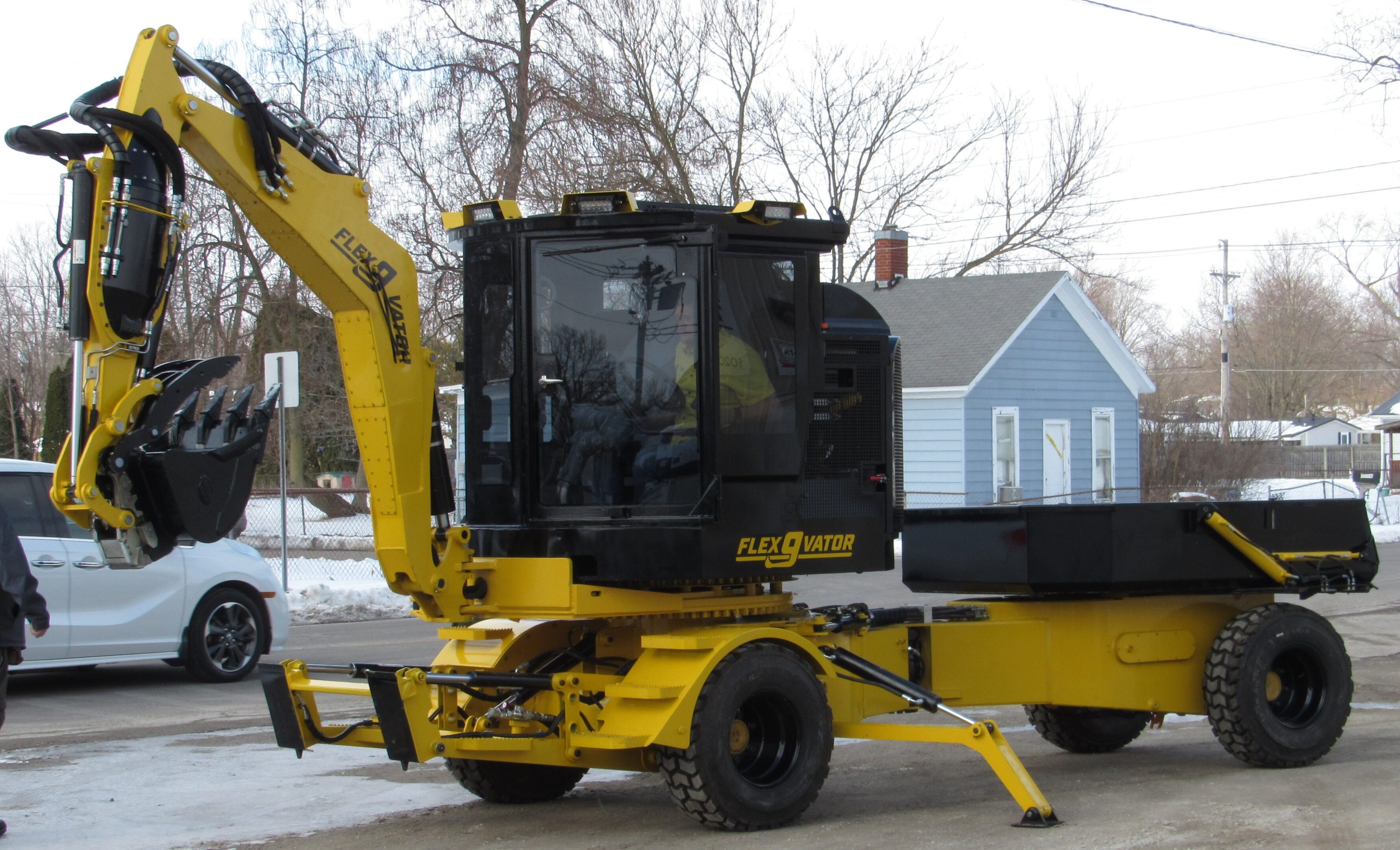 Yellow wheeled excavator parked on street